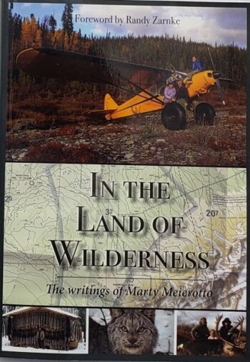 Book cover for "In The Land of Wilderness | The Writings of Marty Meierotto" with an airplane, map, cabin, and wild animal.