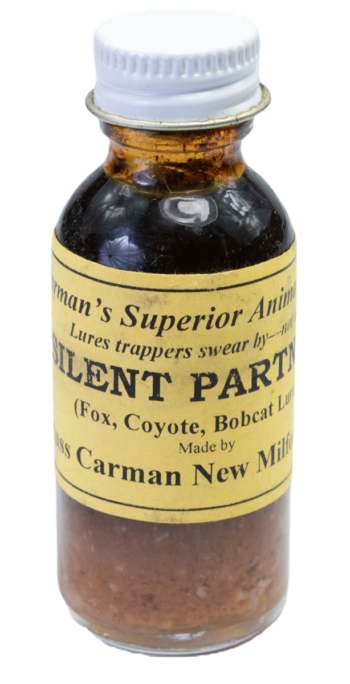 Small glass bottle labeled "Carman's Silent Partner Lure," used for trapping fox, coyote, and bobcat.