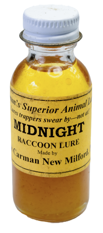 A small glass bottle labeled "Carman's Midnight Coon Lure" with yellow liquid, sealed with a metal cap.