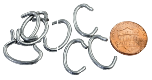 A set of small open metal Trap Tag Fasteners, similar to a copper coin for size comparison, lies scattered.