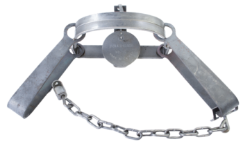 Metal animal trap, jaws open, chain attached, round plate labeled Bridger #4 Long Spring Trap Made in Canada.